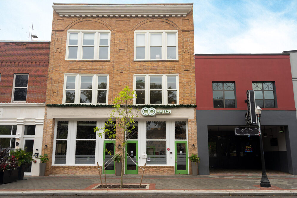 The brick COhatch Lakeland facade and green entrance doors at 211 East Main Street